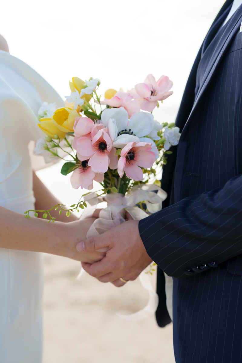 重なる二人の手元に宿る愛。彩り豊かなブーケと共に