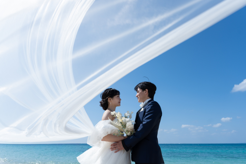 青空と青い海にベールが描く幻想的なおふたりの誓い