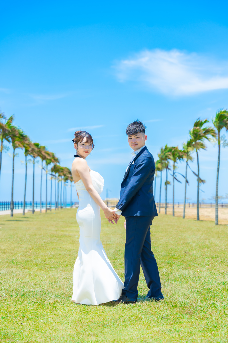ヤシの木の下で振り返るおふたりの自然な笑顔が素敵