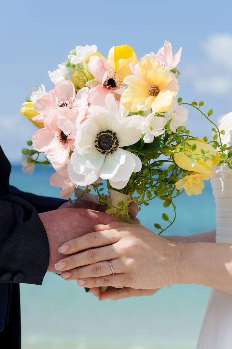 輝く結婚指輪とカラフルなブーケを包む手元ショット