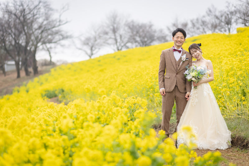 菜の花に囲まれ、肩を寄せ合う幸せの笑顔