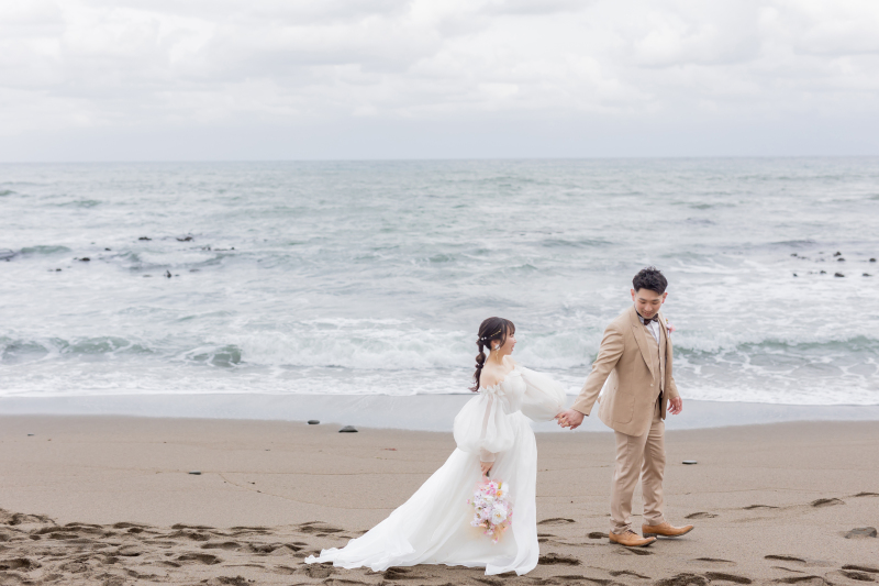 広大な海を背に手をつなぎ歩む海岸ロケ