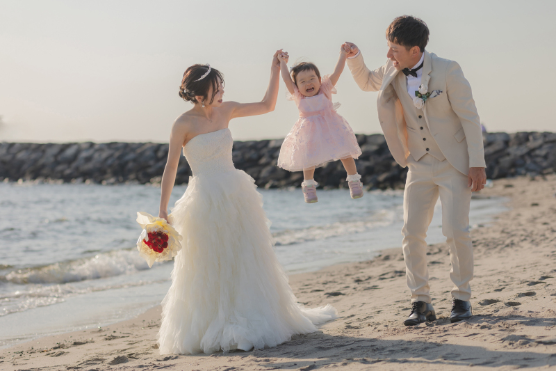 家族みんなで手をつなぎ、笑顔溢れる海辺。