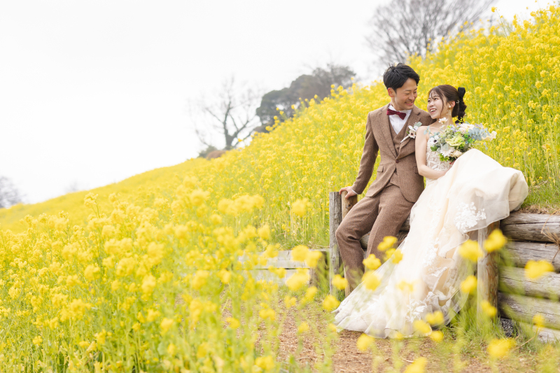菜の花畑に囲まれて、見つめ合う笑顔の2人