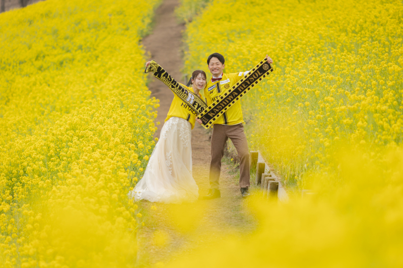 ユニフォーム姿で掲げる、菜の花畑の応援