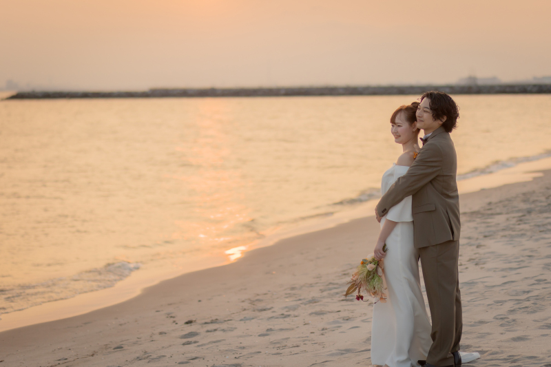 夕光の海辺で優しく抱き合うロマンチックフォト