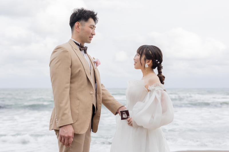 エコー写真を手に未来を祈る砂浜ポートレート