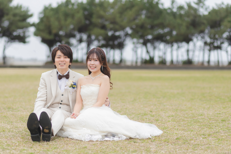 芝生に座って寄り添う、ナチュラルな笑顔