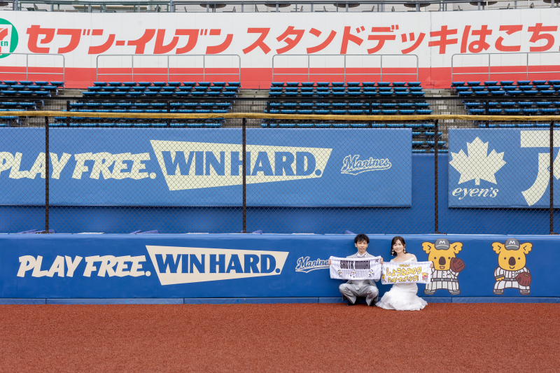 応援タオルを掲げるフェンス前の笑顔ポートレート