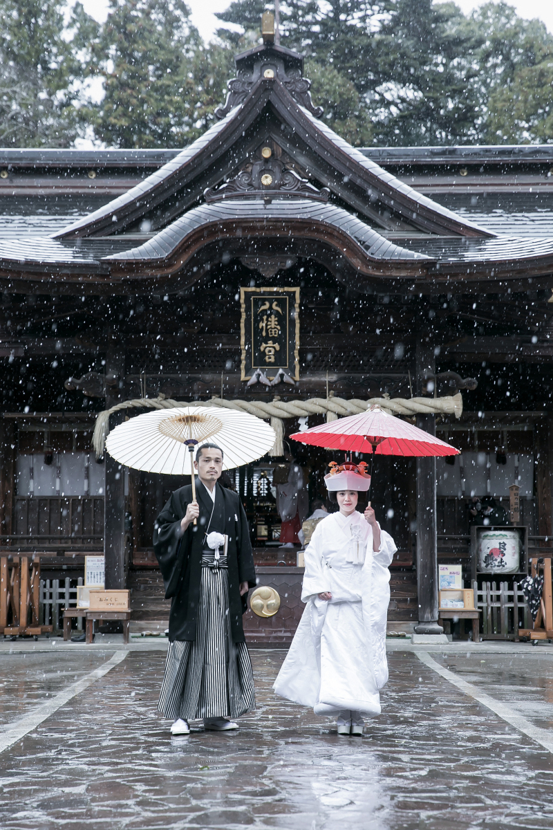 神前式終わった直後の写真です。雪のため番傘をさして神殿から出てきたおふたり。その光景が魅力的で帰りの道中、おふたりを止めて撮らせてもらった一枚です。