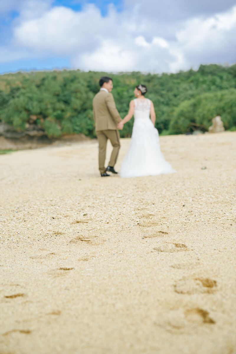 砂浜に残る二人の足跡と手を繋いだ幸せな後ろ姿