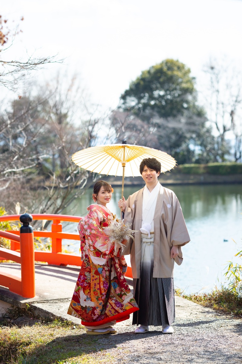 赤い橋の横で和傘を持って