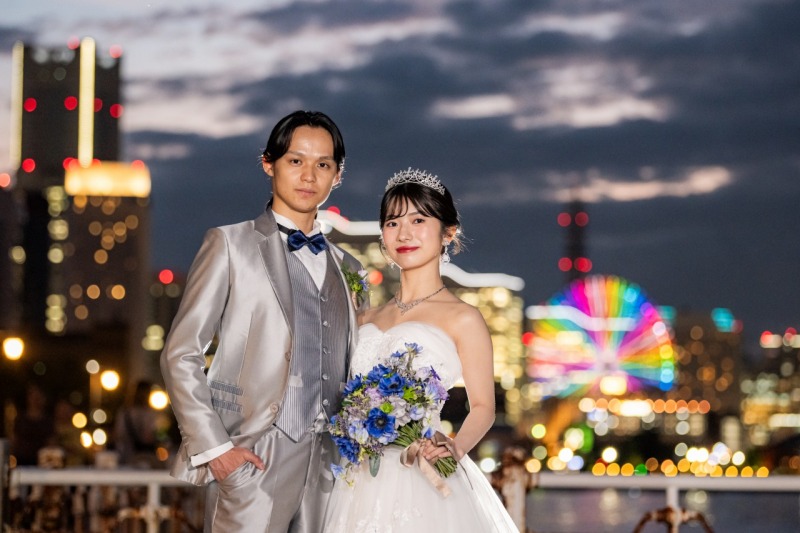 観覧車の灯りを背景に並ぶ、おふたりのみなとみらい