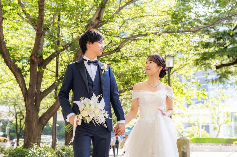 新緑の木漏れ日の中、見つめ合いながら歩くふたり。