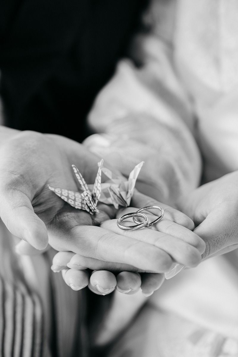 結婚指輪と折り鶴を添えた手元フォト