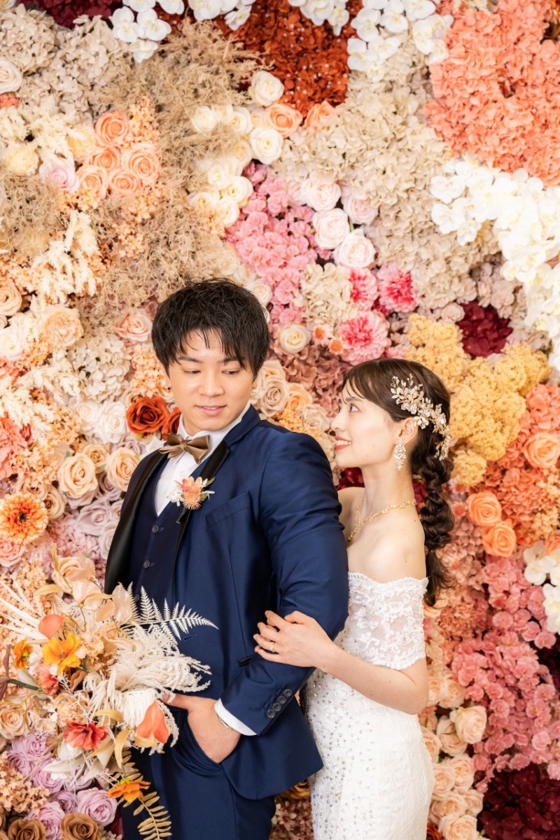 色彩豊かな花壁が彩る自然な笑顔のウェディング写真