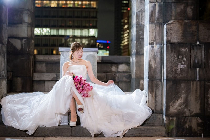 都会の夜景に映えるドレスの広がりが印象的な一枚。