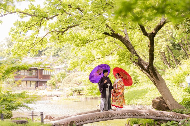 新緑に包まれた庭園で赤と紫の和傘と過ごすひととき
