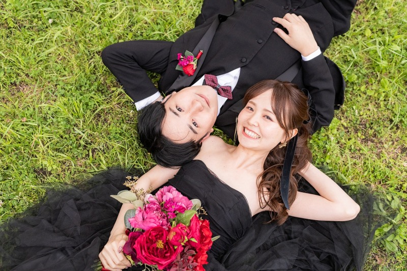 芝生に寝転び笑顔を交わす自然体のおふたり