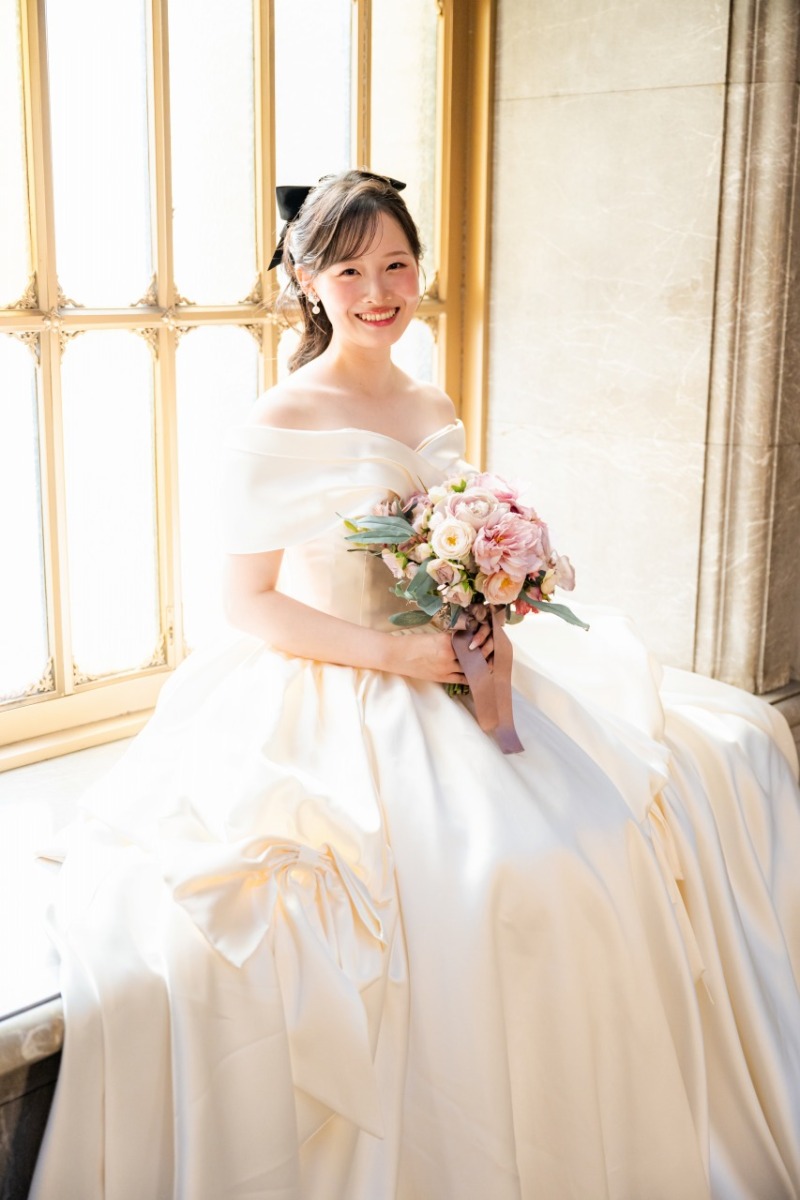 窓辺のやわらかい光に包まれて見せるご新婦様の笑顔