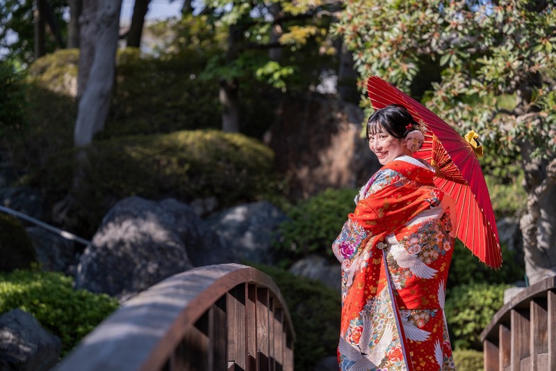 赤い和傘と笑顔が映えるご新婦様の振り返りショット