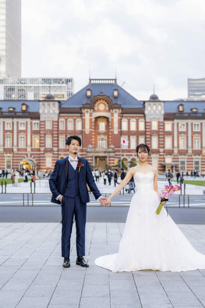 昼間の東京駅前で手をつないだショット