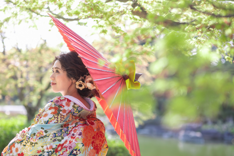 柔らかな光と新緑に包まれて、一瞬の静けさが形になったような美しいお写真になりました。色鮮やかな着物と赤い和傘の調和で、優雅で心に残る情景を生み出しています。
