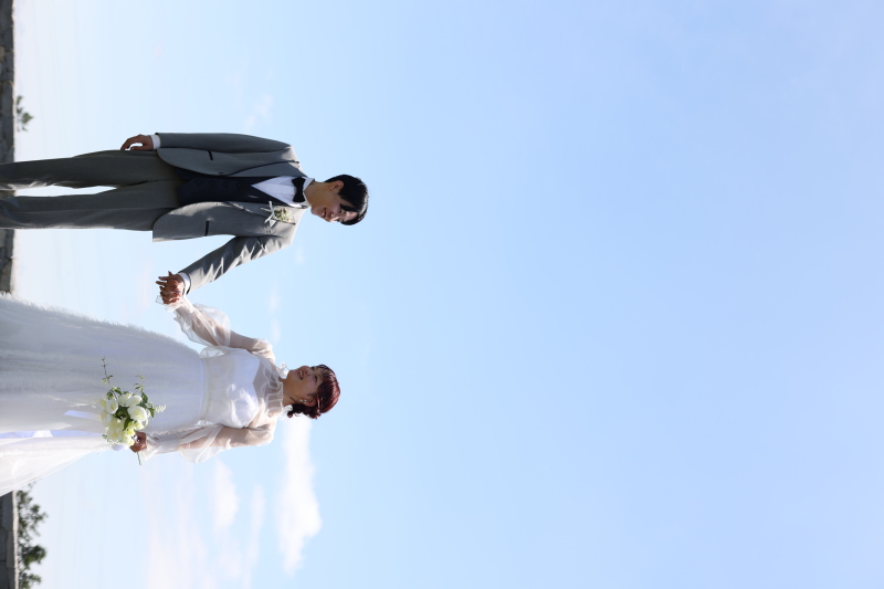 青空の下で手を繋ぎ歩む二人の特別な一枚!