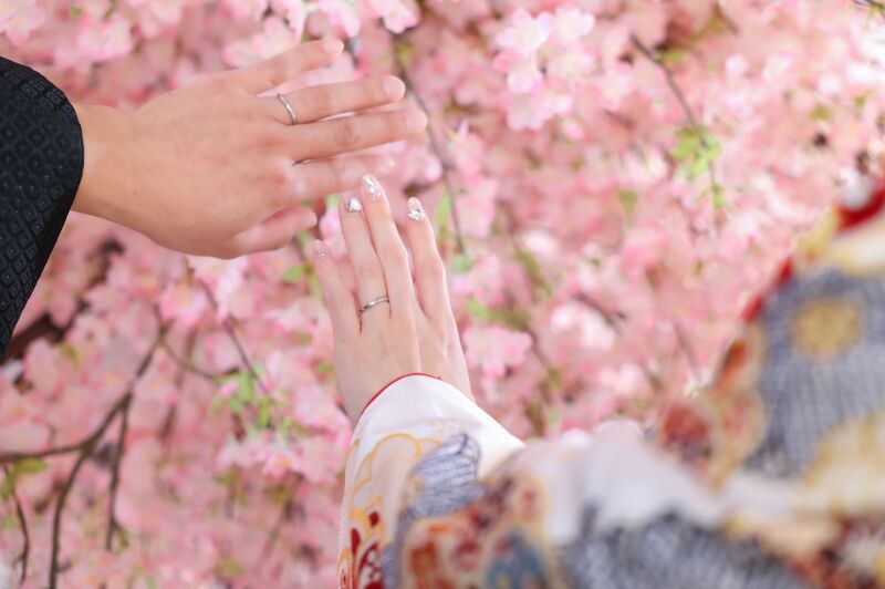 桜を背景に披露する手元と結婚指輪のアップ