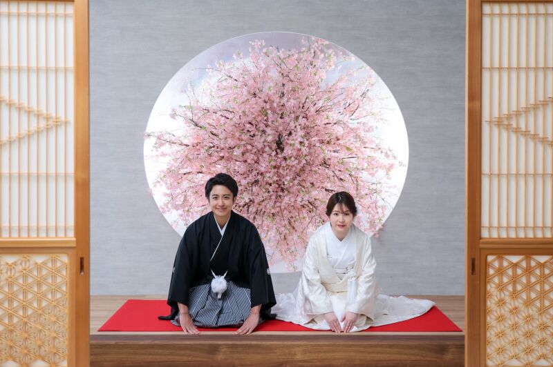 桜の丸窓を背景に正座でご挨拶