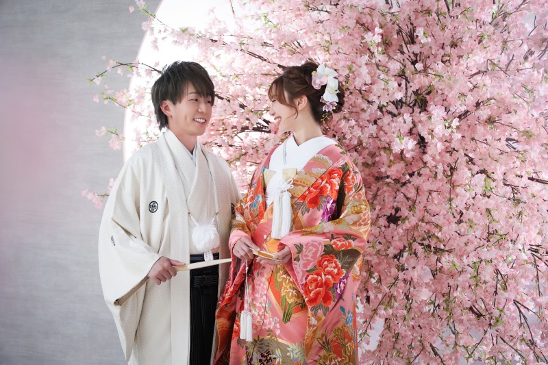 桜の前でにこやかに