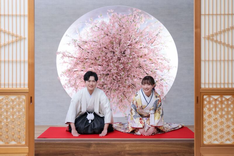 桜の丸窓背景に映える、和やかな正座のご挨拶ポーズ