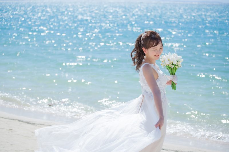 太陽の光を浴びて、キラキラと輝くビーチ。その中で、ひときわ美しく佇む新婦様。風になびくドレスが、その美しさをさらに際立たせます。自然の美しさと新婦様の美しさが調和した、ため息が出るほど美しい一枚です。