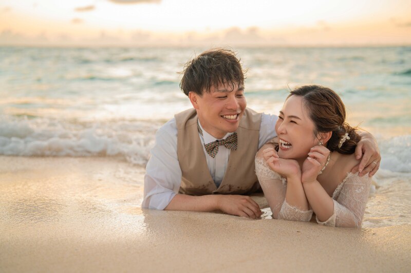 夕陽に染まる砂浜でおふたりの笑顔が輝く、まるで映画のワンシーンのような1枚！自然体で心から楽しんでいる様子が伝わってきて、波打ち際の穏やかな雰囲気とおふたりの温かな表情が完璧に調和しています。