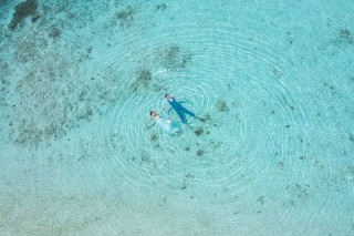 ウォーターイン撮影とドローンフォトが織りなす最高のハーモニー。海に浮かぶおふたりを、空から見下ろすダイナミックな構図は、まるで楽園にいるかのよう。この非日常的な美しさは、ずっと眺めていたくなるはずです