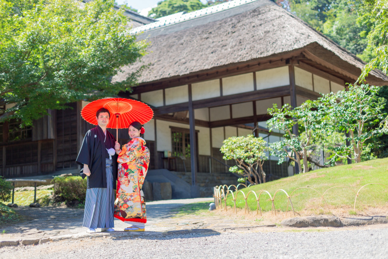 茅葺き屋根の前で。