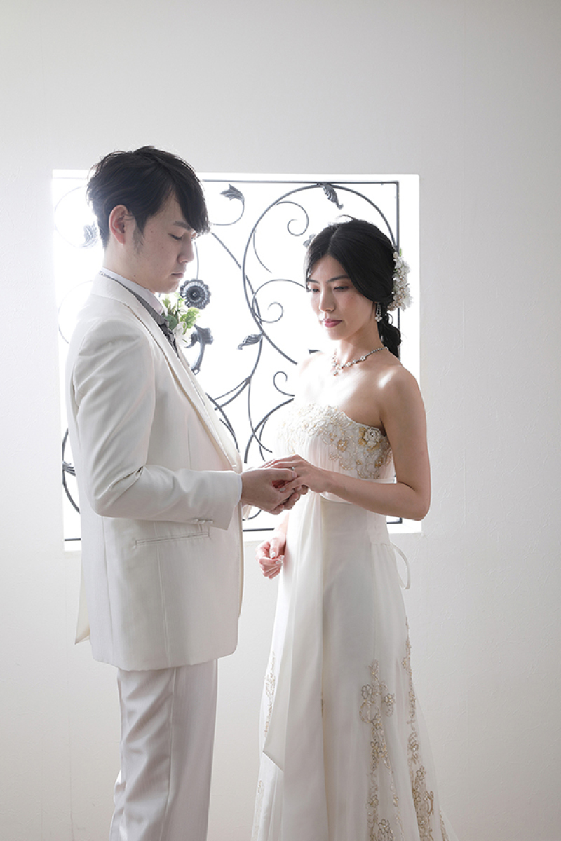 光の差し込む窓の前で指輪交換しているかのように