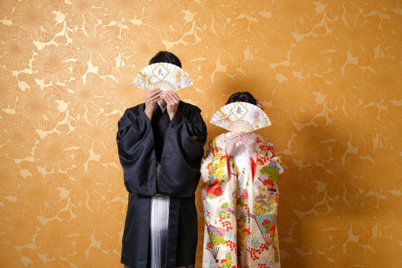 「夫」「妻」の扇子を持って