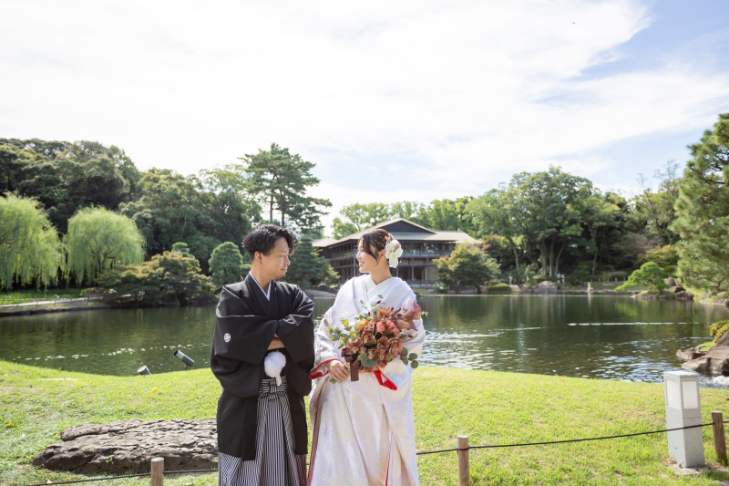 庭園で池畔に並ぶ二人の晴れ姿を永遠に刻む記念写真