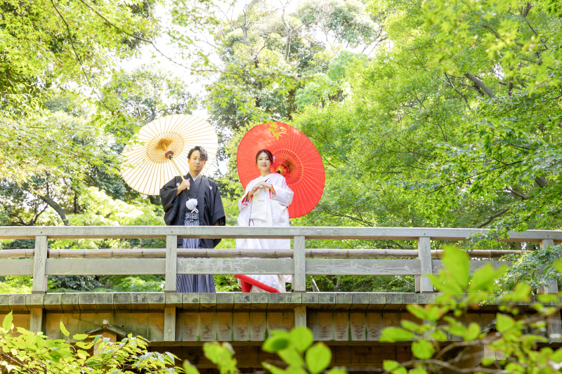 緑に包まれた橋の上で和傘が彩る晴れの一枚