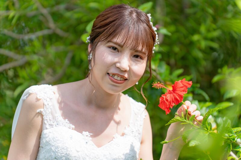 ハイビスカスをそっと手にした新婦様の笑顔