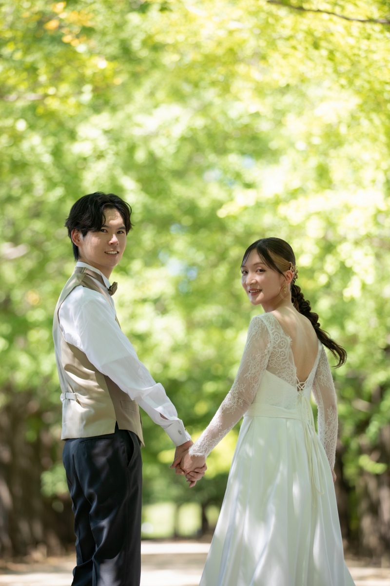 緑の木漏れ日の中で、手を取り合い微笑む二人