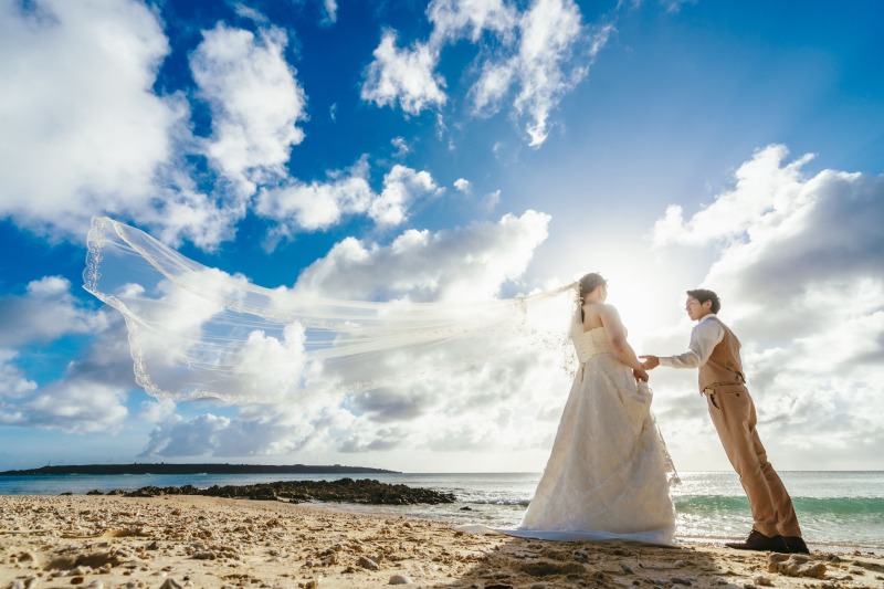 青空の下に舞うウェディングベールが美しい