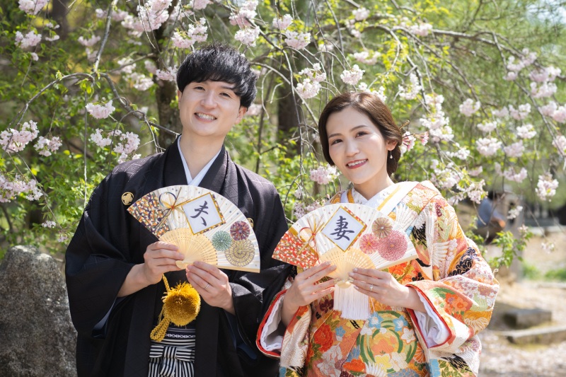 上品な八重桜の前で扇子を使って