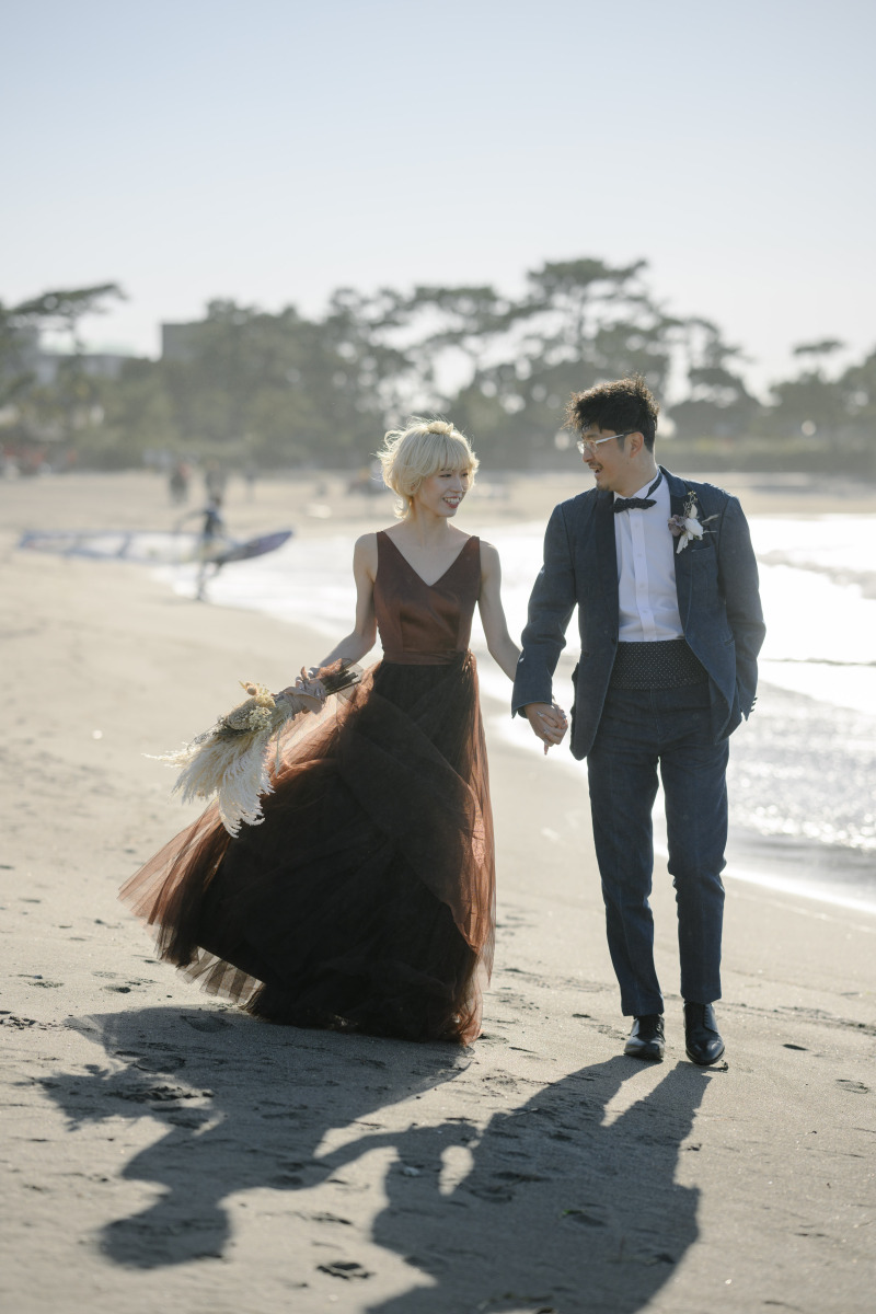 個性的なブラウンカラーのドレスが波打ち際に映えて