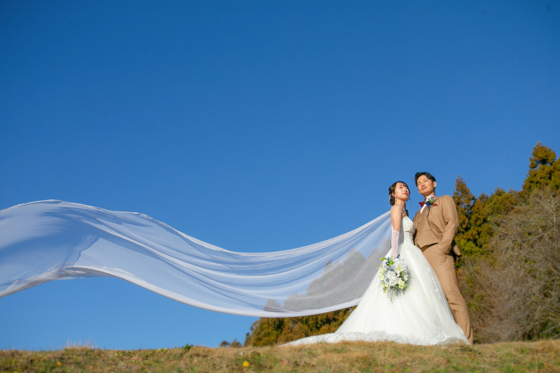 風になびくベールと青空に包まれた、おふたりらしい自然な瞬間を切り取りました。