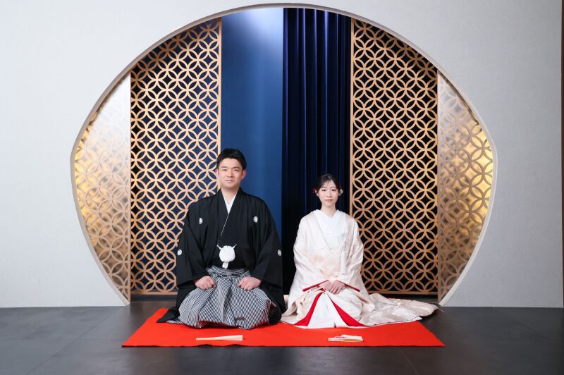 丸窓モチーフの前で正座する伝統的なお辞儀姿