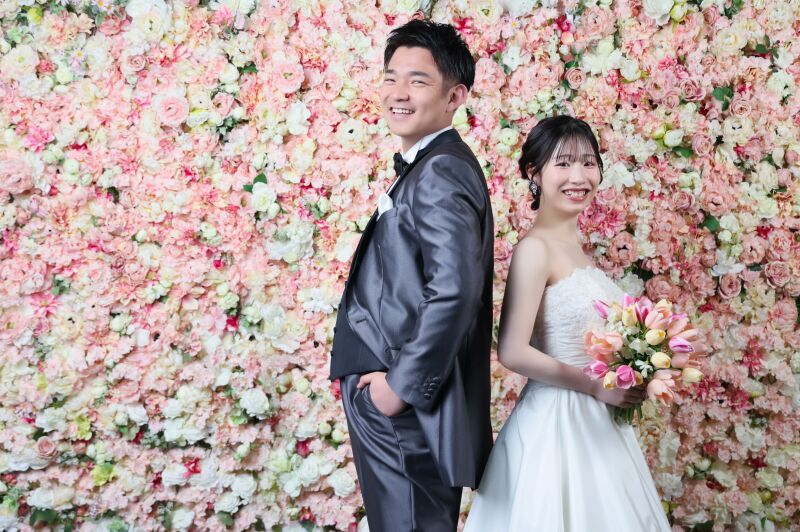 お花に囲まれた背景で弾ける笑顔のお二人