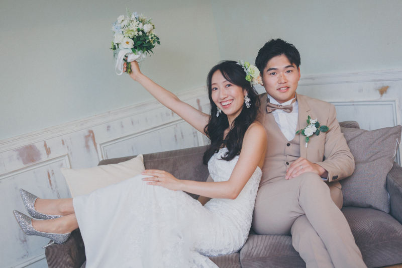 ナチュラルな笑顔が輝く、リラックス感あふれるソファショット!新婦様のブーケを高く掲げるポーズがとても印象的で、祝福ムードいっぱいの一枚に仕上がりました!