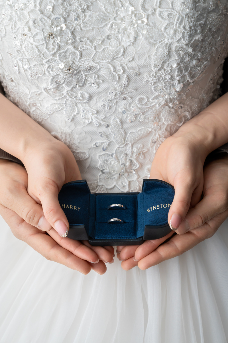 白いレースの上で指輪を包む手元